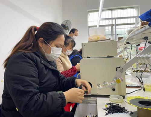 工人们在全面落实疫情防控措施的基础上,正在"微工厂"里加工电子产品